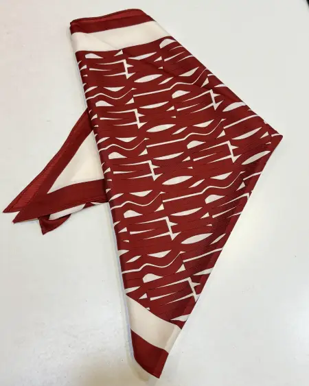 Pañuelo burdeos con estampado geométrico tipo tipografía en crudo y bordes combinados. Moderno y llamativo.